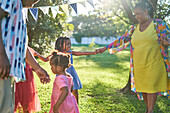 Happy grandmother and granddaughter dancing in backyard