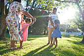 Family dancing in sunny backyard grass