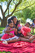 Happy family relaxing on blanket in park