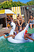 Happy sisters playing on inflatable swan in swimming pool