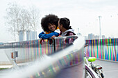 Teen friends talking on urban footbridge