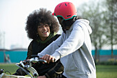 Happy teen friends riding bicycles in park