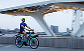 Man riding illuminated bicycle along city waterfront