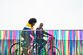 Teenage friends riding bicycles on modern footbridge
