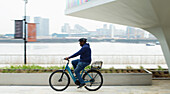 Man riding bicycle along city waterfront