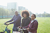Happy family with bicycles in sunny urban park