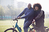 Happy father and teen son on bicycles in urban park