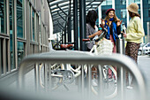 Young female friends talking at bike rack in city
