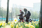 Teen friends with bicycles in sunny urban park