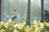 Happy teen friends riding bicycles in sunny park