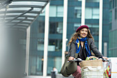 Happy young woman riding bicycle with groceries in city