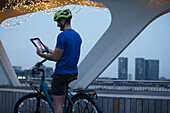 Man on bicycle video chatting in city at night