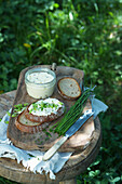 Bread with herb cream cheese on wooden stool outside