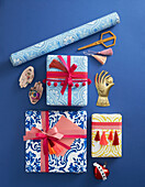 Verpackte Geschenke mit Pomponborte und Quaste dekoriert, Tapetenrolle und Dekoobjekte