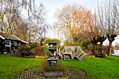 Urn in autumnal garden with summerhouse by a lake