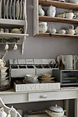 Shelves with porcelain dinnerware in the kitchen in shabby chic style