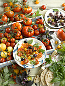 Ingredients for caprese salad and a plate with tomatoes, mozzarella, basil, olives