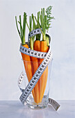 Carrots in a glass, wrapped in a measuring tape