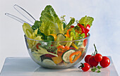 A bowl of mixed lettuce with tomatoes beside it