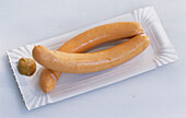 Two Vienna sausages with mustard on paper plates