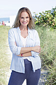 Langhaarige Frau in frühlingshaftem blau-weißem Outfit am Strand