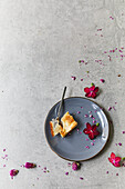 Ein Stück Mohn-Quark-Kuchen vom Blech mit Blüten