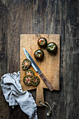 Whole and sliced green tomatoes on a rustic wooden chopping board