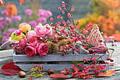 Duftende Herbstdekoration mit Quitten, Äpfeln, Kastanien, Pfaffenhütchen (Euonymus europaeus) und Rosenblüten
