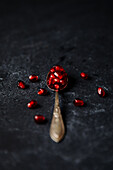 Spoon with pomegranate seeds on a dark background