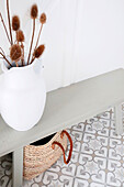 White vase with dried plants on a grey console in the cloakroom area