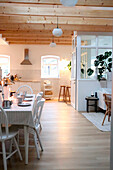 Dining area with white Scandinavian-style table and wooden chairs overlooking the kitchen