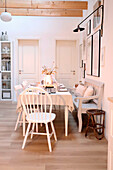 Scandinavian-style dining area with white wooden table, chairs and bench seat