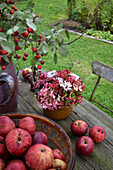 Hortensienstrauß und rote Äpfel auf Gartentisch