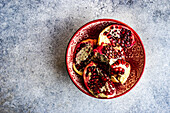 Ripe organic pomegranate fruit on red ceramic bowl