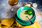 Cheese cream soup with fresh herbs, garlic and glass of white dry wine