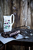 Haselnussschokolade, Zweig mit weißen Blüten und Keramikkrug auf rustikalem Holztisch