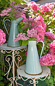 Jug vases of hydrangeas on ornate tables in garden