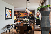 Glass pendant lamps above dining table, modern artworks and slate wall in open-plan interior