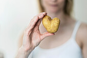 Die Hand der Frau, die herzförmige Kartoffel hält