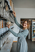Lächelnde Verkäuferin, die Lebensmittelspender benutzt, während sie in einem Zero-Waste-Laden arbeitet