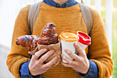 Young man with croissant and coffee to go