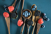 Blueberries, blackberries and raspberries on different spoons