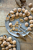 Whole and cracked organic walnuts and nutcracker on tin plates
