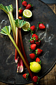 Frischer Rhabarber, Erdbeeren, Zitrone und Limette auf rustikalem Backblech