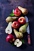 Sliced and whole apples and pears on dark ground