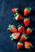 Sliced and whole strawberries on dark ground