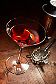 Martini or Manhattan drink with bar utensils on wooden counter
