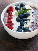 Bowl of blueberry smoothie with chia, coconut flakes, almonds and Japanese Wineberries