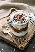 Coconut yoghurt and chocolate chia seed dessert with banana, topped with cacao nibs and hazelnuts