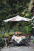 DIY-Sonnenschirm über Gartentisch mit Blumenstrauß, Erdbeerkuchen und Kaffeegeschirr